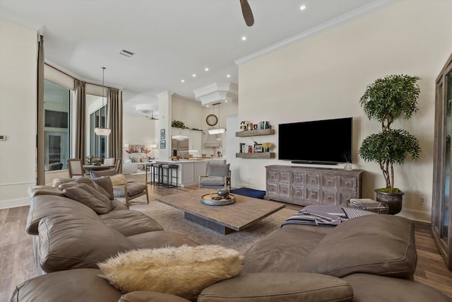 living room featuring hardwood / wood-style floors, ceiling fan, and crown molding