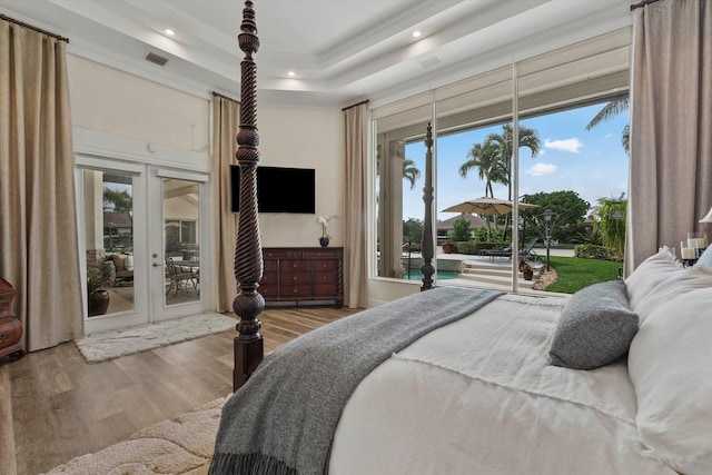 bedroom with hardwood / wood-style floors, french doors, crown molding, access to exterior, and a tray ceiling