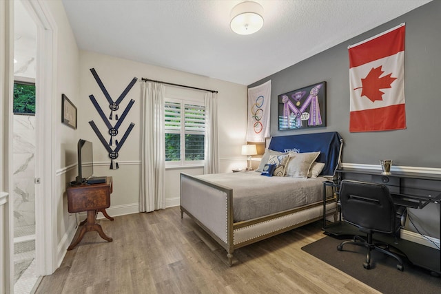 bedroom featuring ensuite bath and hardwood / wood-style floors