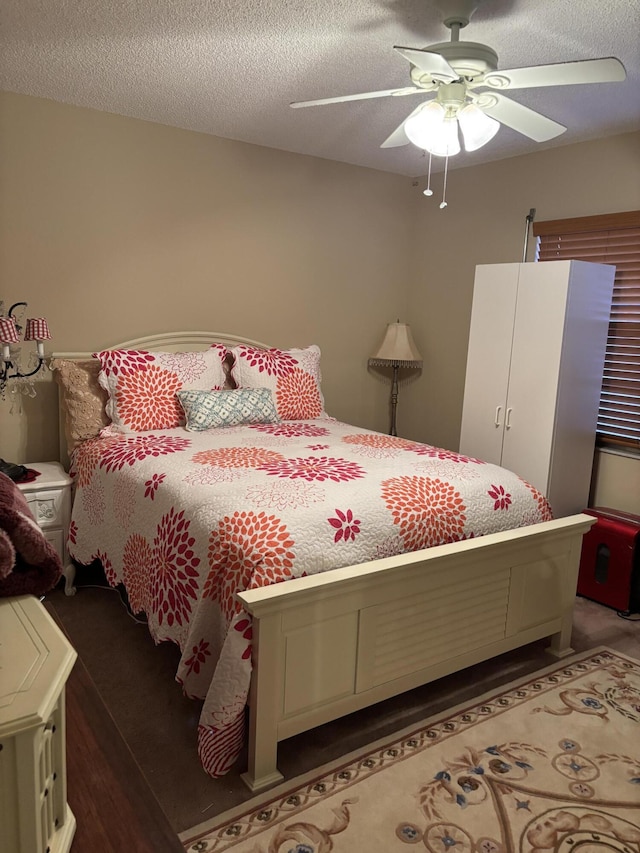 bedroom with a textured ceiling, ceiling fan, and dark wood-type flooring