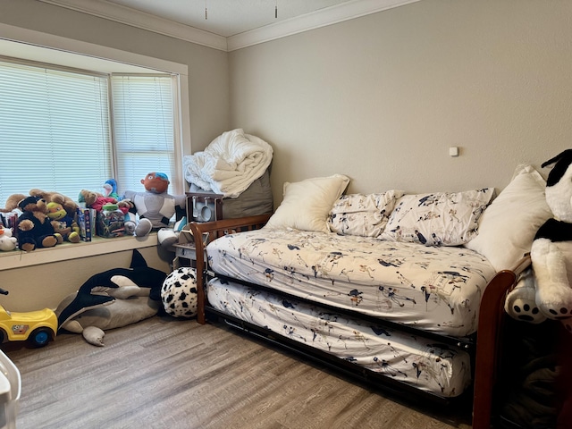 bedroom with ornamental molding and wood finished floors