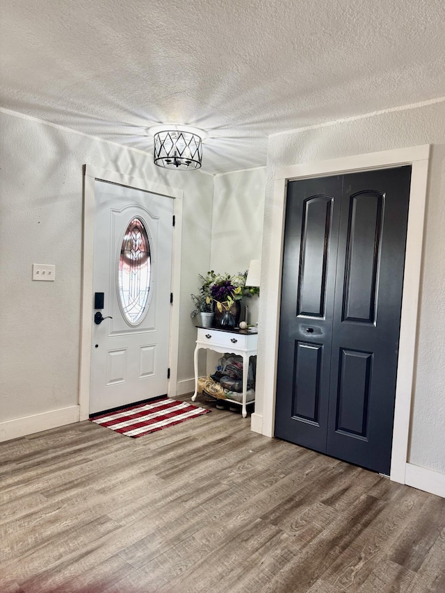 entryway with a textured ceiling, baseboards, and wood finished floors