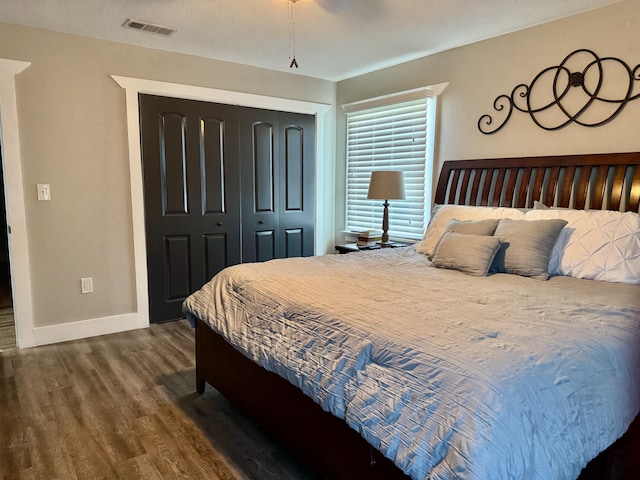 bedroom with a closet, visible vents, dark wood finished floors, and baseboards