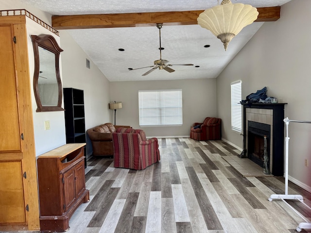 living area featuring vaulted ceiling with beams, a textured ceiling, and a fireplace