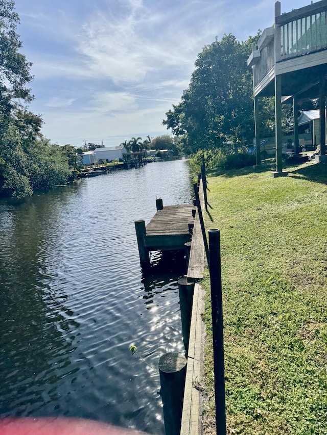 view of dock with a yard and a water view