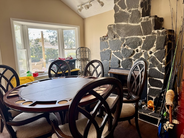 dining space with vaulted ceiling, a textured ceiling, and track lighting