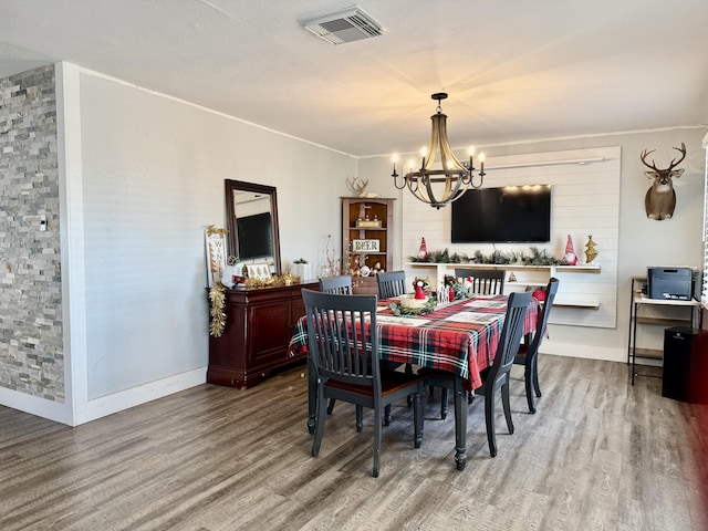 dining space with baseboards, wood finished floors, visible vents, and a notable chandelier