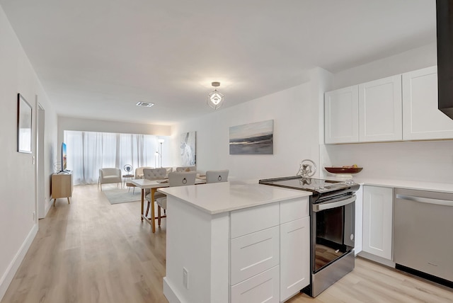 kitchen with kitchen peninsula, white cabinetry, stainless steel appliances, and light hardwood / wood-style flooring