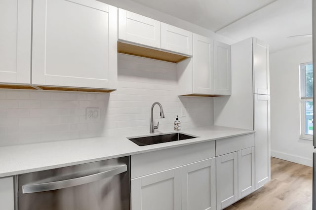 kitchen featuring backsplash, sink, stainless steel dishwasher, light wood-type flooring, and white cabinetry