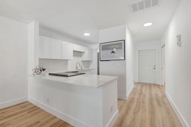 kitchen featuring light hardwood / wood-style floors, sink, white cabinetry, and kitchen peninsula