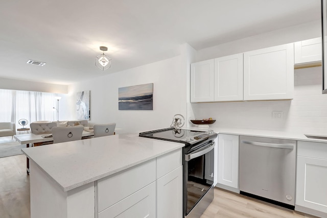 kitchen with decorative backsplash, light hardwood / wood-style flooring, white cabinets, and appliances with stainless steel finishes