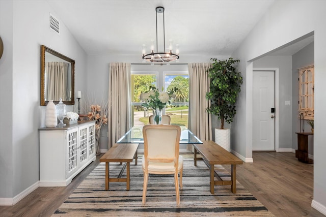 dining area with lofted ceiling, dark wood-type flooring, and a chandelier