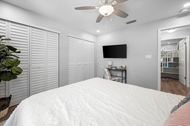 bedroom with ceiling fan, dark hardwood / wood-style flooring, and multiple closets