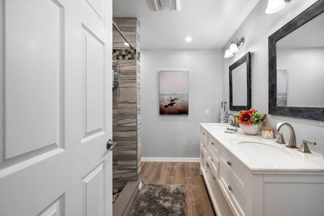 bathroom with hardwood / wood-style floors, vanity, and tiled shower