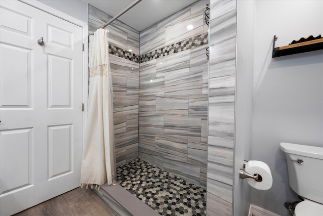 bathroom with hardwood / wood-style flooring, curtained shower, and toilet