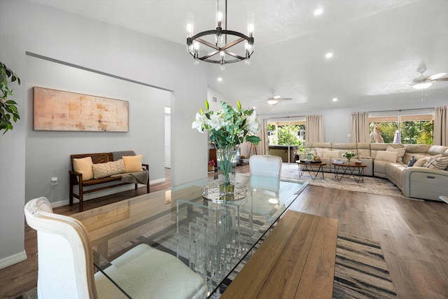 dining room with ceiling fan with notable chandelier, hardwood / wood-style flooring, and vaulted ceiling