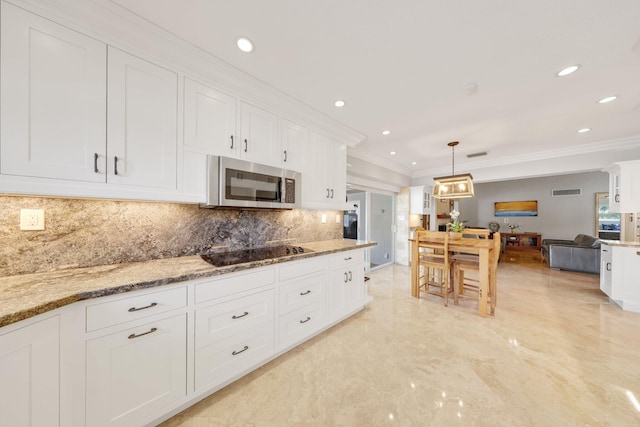 kitchen featuring stainless steel microwave, crown molding, white cabinetry, and black electric cooktop