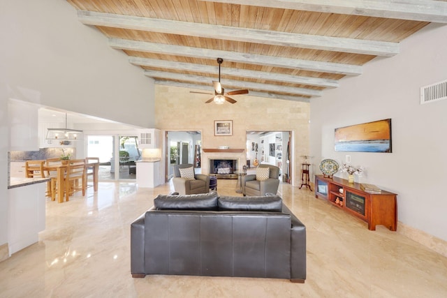 living room with beam ceiling, ceiling fan with notable chandelier, wooden ceiling, and a towering ceiling