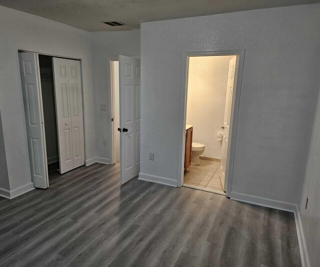 unfurnished bedroom featuring a closet, dark hardwood / wood-style flooring, and ensuite bathroom