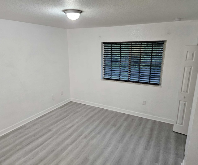 unfurnished room with hardwood / wood-style floors and a textured ceiling