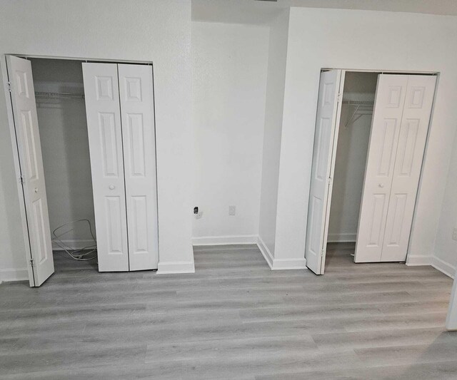 unfurnished bedroom featuring two closets and light hardwood / wood-style flooring