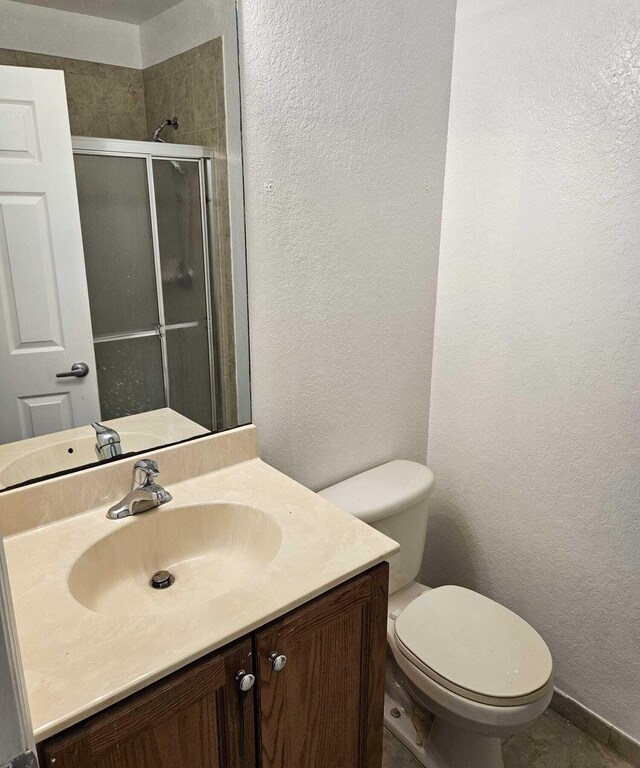 bathroom featuring vanity, an enclosed shower, and toilet