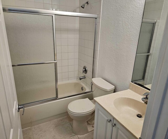 full bathroom with tile patterned floors, vanity, toilet, and bath / shower combo with glass door