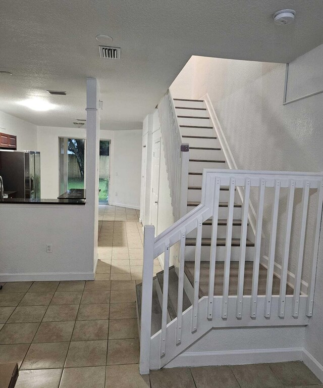 stairs featuring tile patterned flooring and a textured ceiling