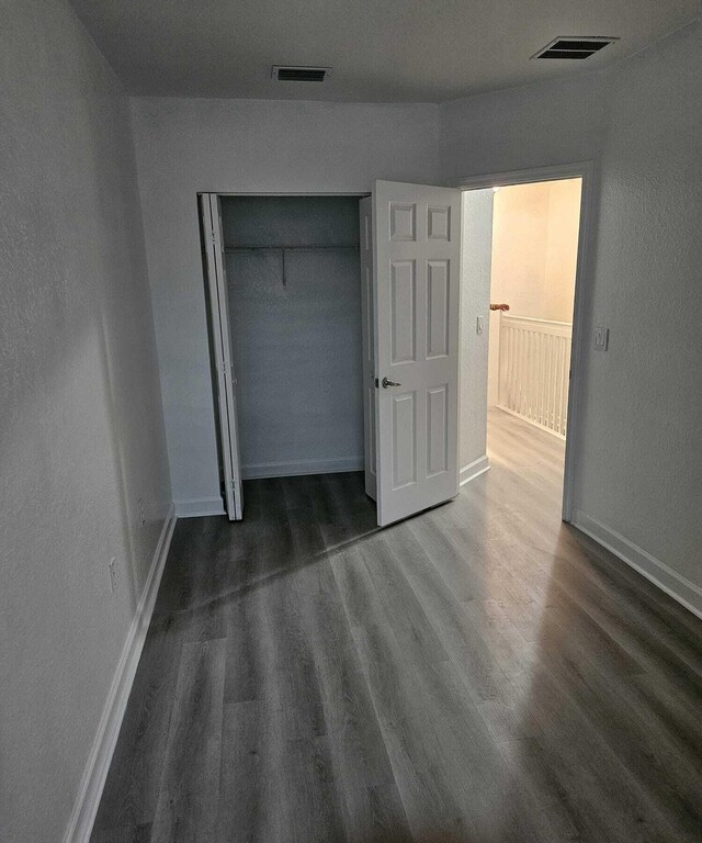 unfurnished bedroom featuring a closet and dark wood-type flooring