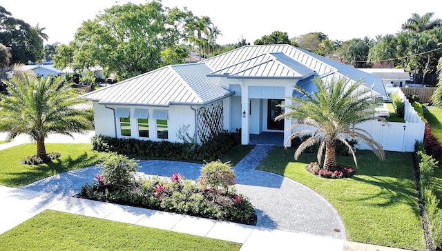 view of front facade featuring a standing seam roof, a front yard, metal roof, and stucco siding