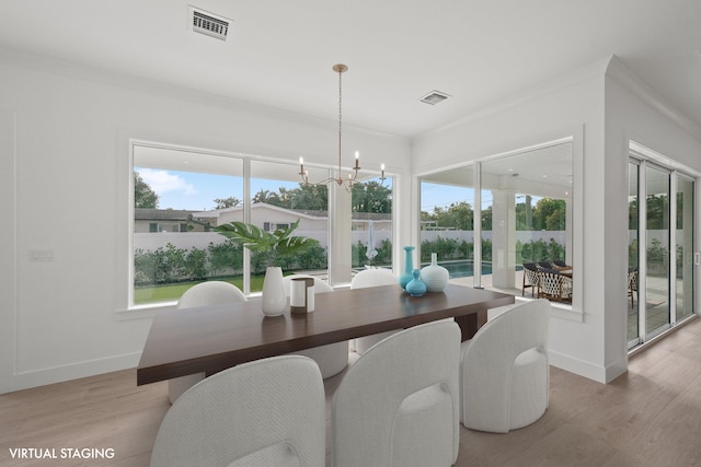 dining area featuring a wealth of natural light, visible vents, light wood-style flooring, and an inviting chandelier