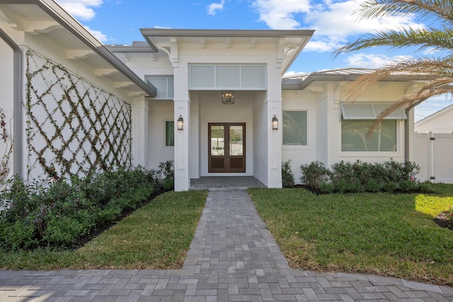 doorway to property featuring a yard, french doors, and stucco siding