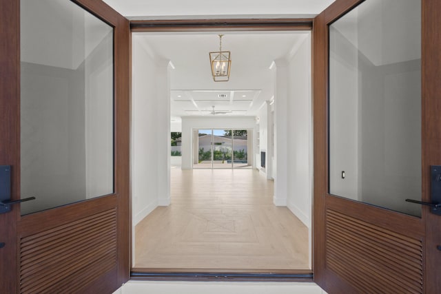 hallway featuring an inviting chandelier and baseboards