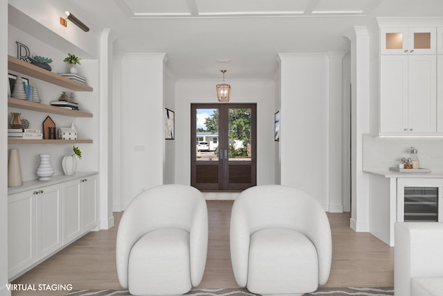 living area with light wood-style floors, french doors, ornamental molding, and baseboards