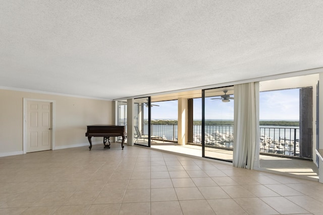 tiled empty room with expansive windows, a water view, a textured ceiling, and ornamental molding