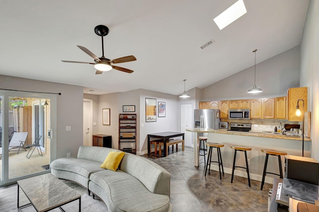 living room featuring a skylight, ceiling fan, and high vaulted ceiling