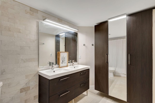 bathroom with tile patterned flooring, vanity, toilet, and tile walls