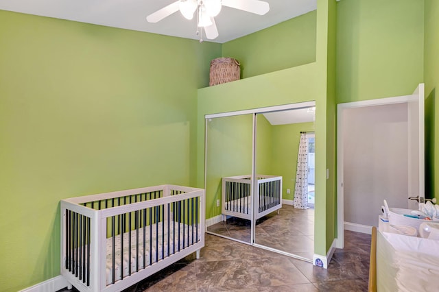 bedroom featuring ceiling fan, a closet, and a crib