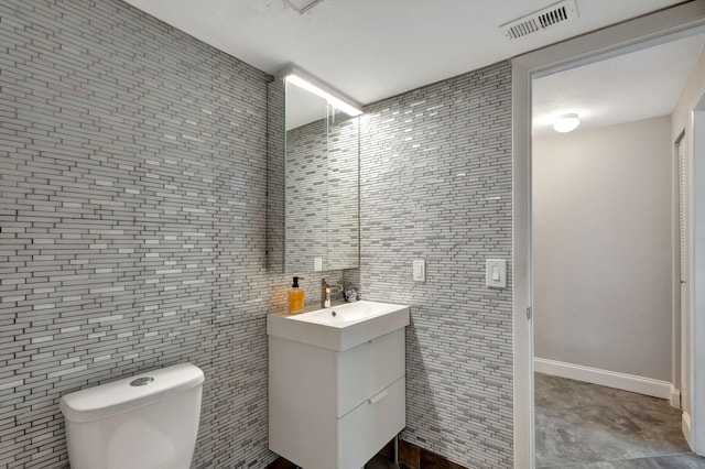 bathroom featuring vanity, toilet, and tile walls