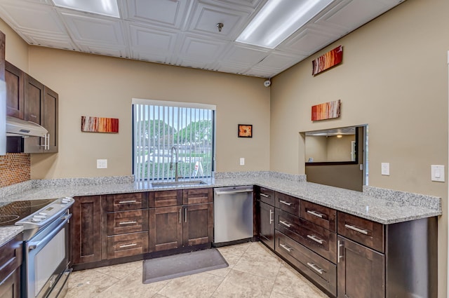 kitchen with kitchen peninsula, light stone counters, stainless steel appliances, sink, and light tile patterned floors