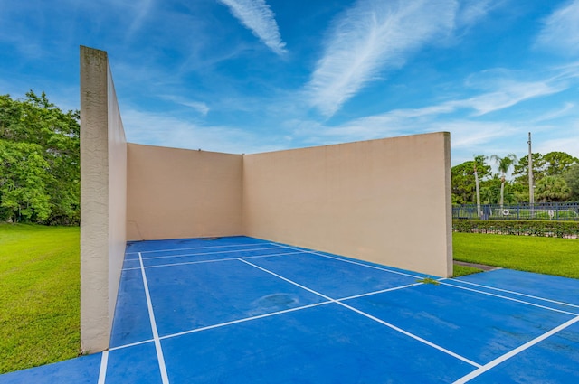 view of tennis court with a yard