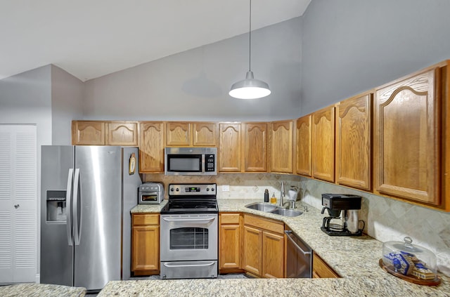 kitchen with light stone countertops, appliances with stainless steel finishes, backsplash, sink, and pendant lighting