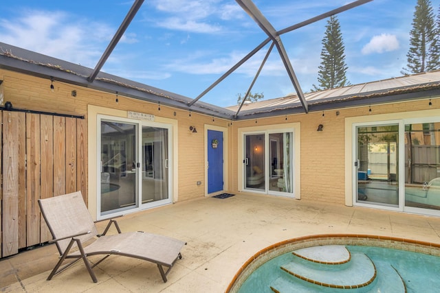 rear view of house with glass enclosure and a patio