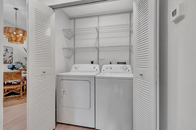 laundry room with separate washer and dryer and light hardwood / wood-style floors