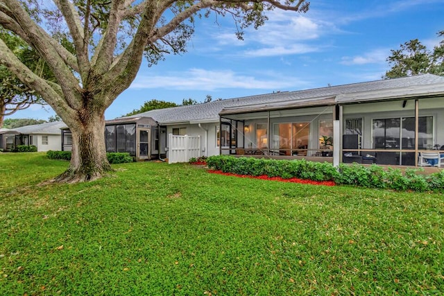 back of property with a lawn and a sunroom