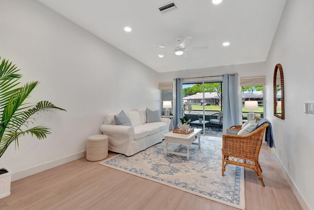 living room with ceiling fan, vaulted ceiling, and light hardwood / wood-style flooring