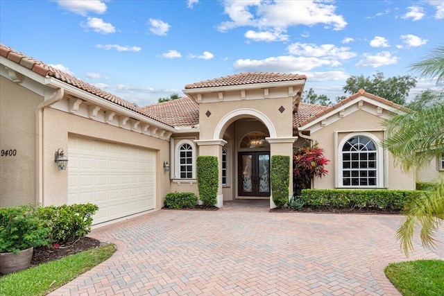 mediterranean / spanish house with a garage and french doors