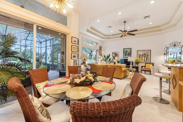 tiled dining room with ceiling fan with notable chandelier, a raised ceiling, a towering ceiling, and crown molding