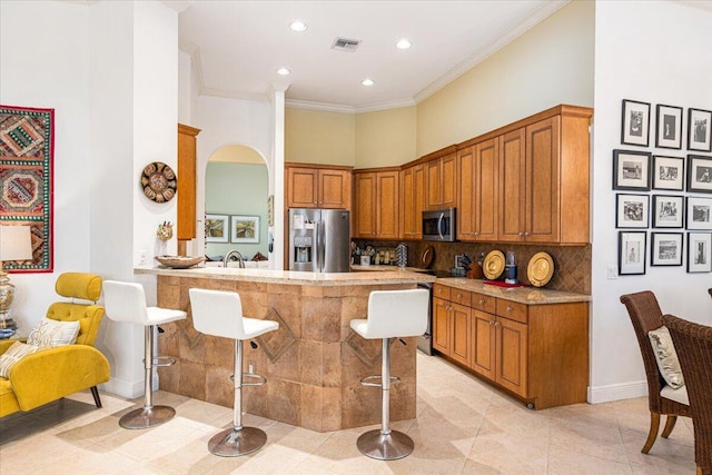 kitchen with backsplash, a kitchen breakfast bar, ornamental molding, appliances with stainless steel finishes, and kitchen peninsula