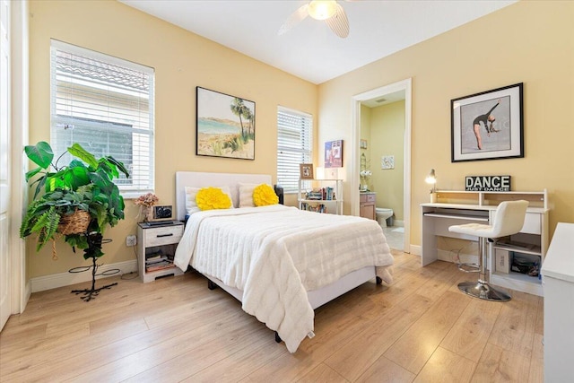 bedroom featuring multiple windows, ceiling fan, ensuite bath, and light hardwood / wood-style floors